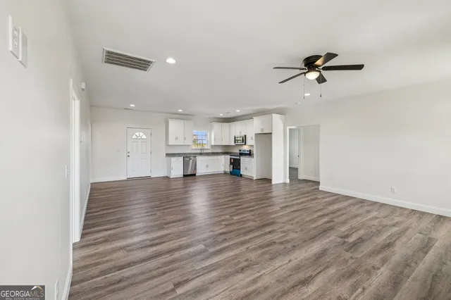 a view of kitchen and empty room with wooden floor