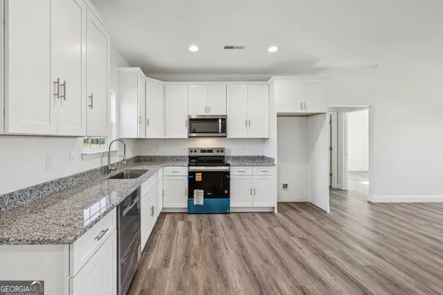 an empty room with wooden floor closet and windows