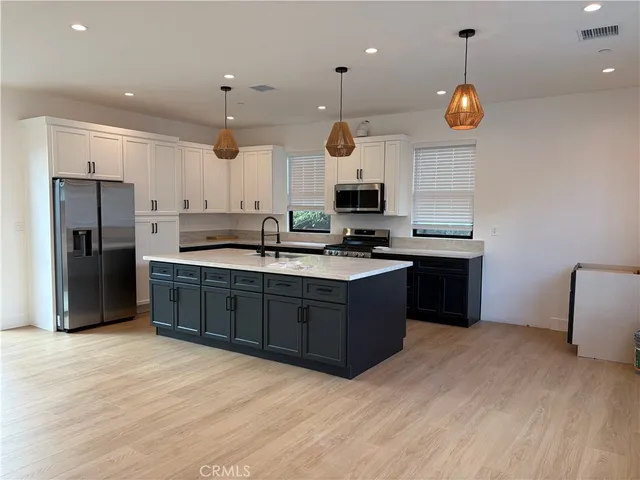 a kitchen with stainless steel appliances granite countertop a sink a stove a refrigerator and island with wooden floor
