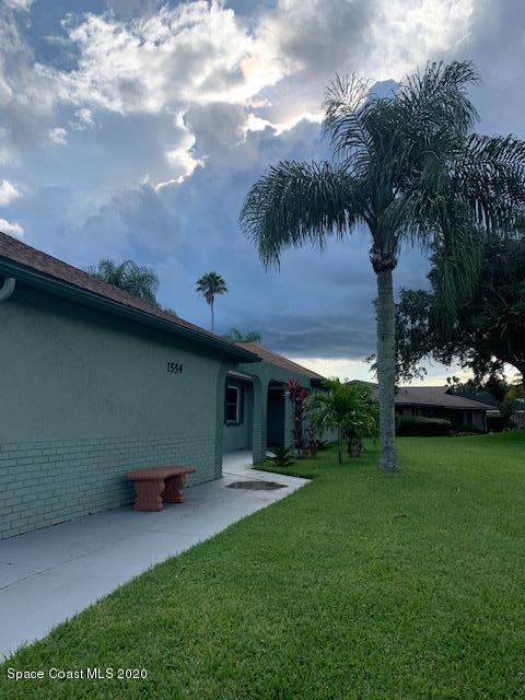 1554 Meadowbrook Road Northeast Palm Bay, FL 32905 - Photo 3 of 37 a backyard of a house with table and chairs plants and large tree