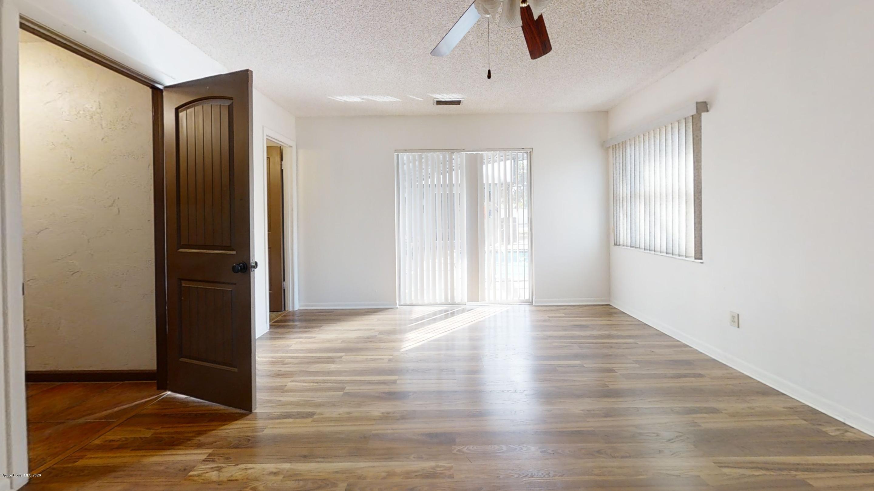 1554 Meadowbrook Road Northeast Palm Bay, FL 32905 - Photo 29 of 37 an empty room with wooden floor and windows