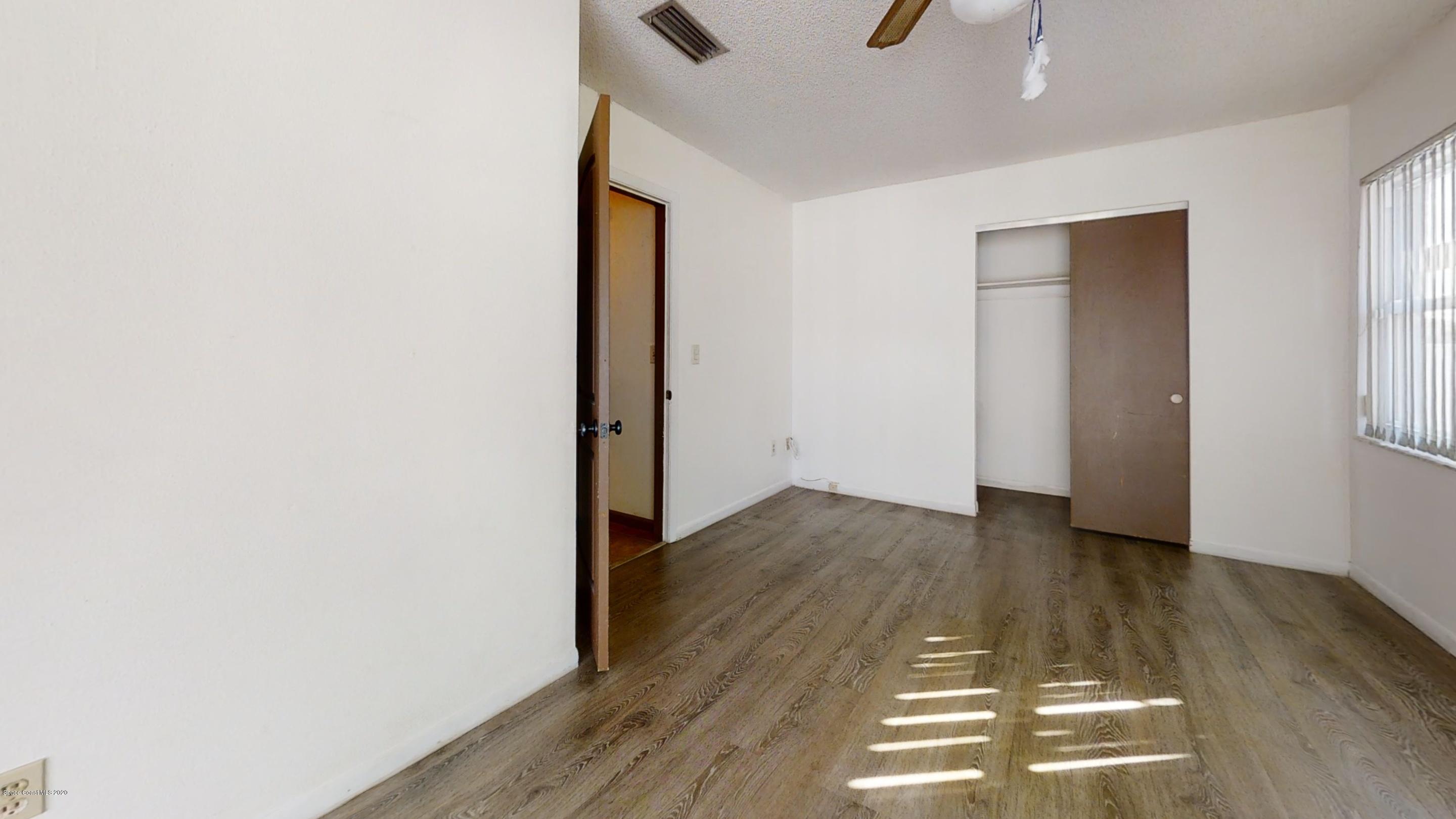 1554 Meadowbrook Road Northeast Palm Bay, FL 32905 - Photo 31 of 37 an empty room with wooden floor and windows