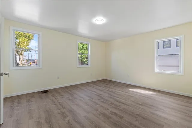 a view of an empty room with window and wooden floor
