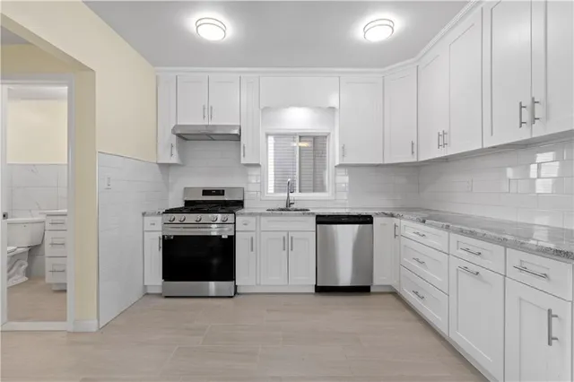 a kitchen with granite countertop white cabinets and stainless steel appliances