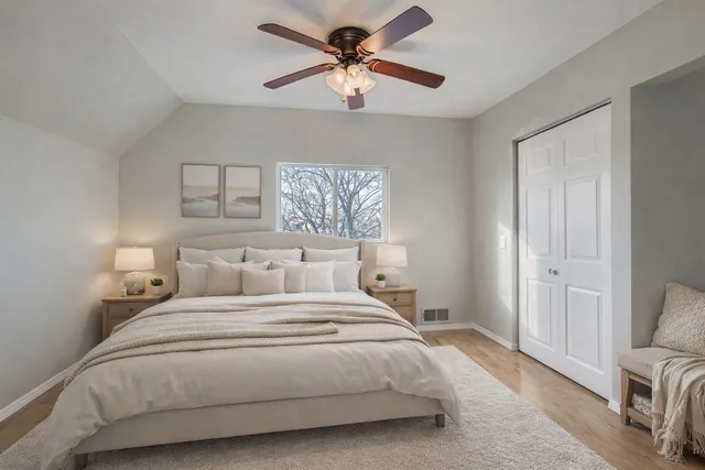 an empty room with a chandelier fan and wooden floor