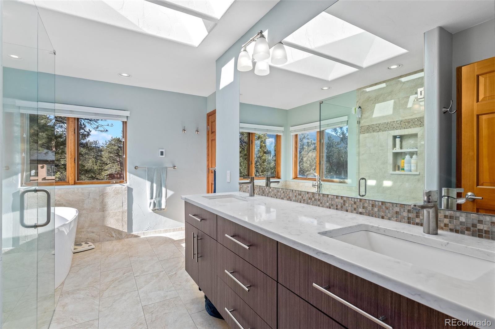 30754 Stratton Court Evergreen, CO 80439 - Photo 23 of 40 a spacious bathroom with a double vanity sink a large mirror and a bathtub