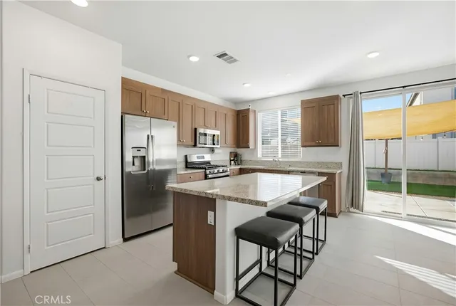 a kitchen with stainless steel appliances granite countertop a stove a refrigerator a sink a dining table and chairs with wooden floor