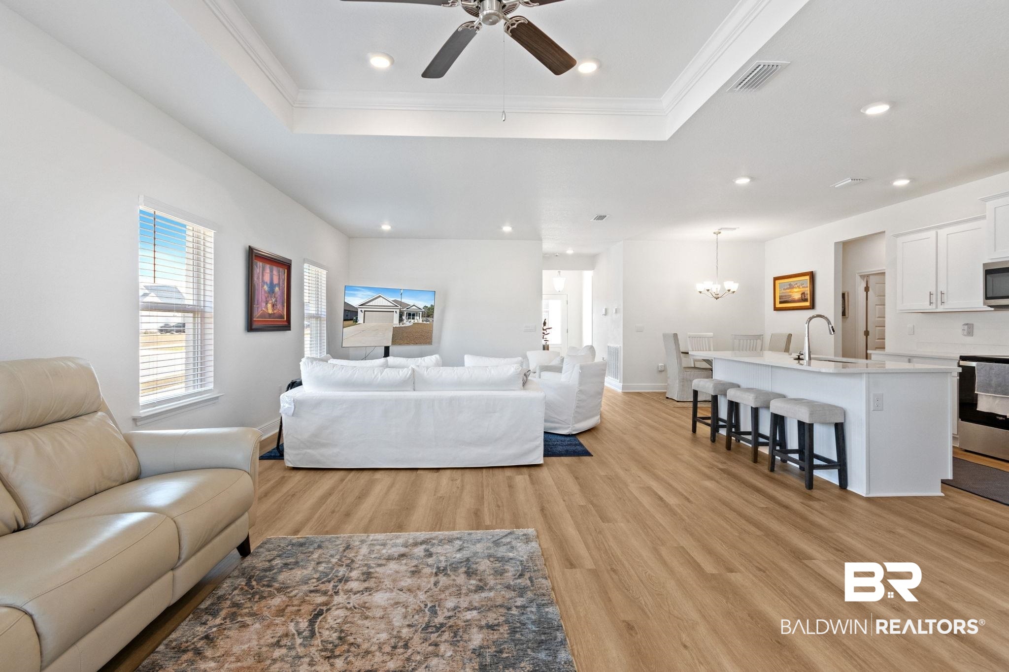 12919 Torrent Road Fairhope, AL 36532 - Photo 22 of 74 Living area featuring suspended lighting, light wood-style floors, healthy amount of natural light, a ceiling fan, and a tray ceiling