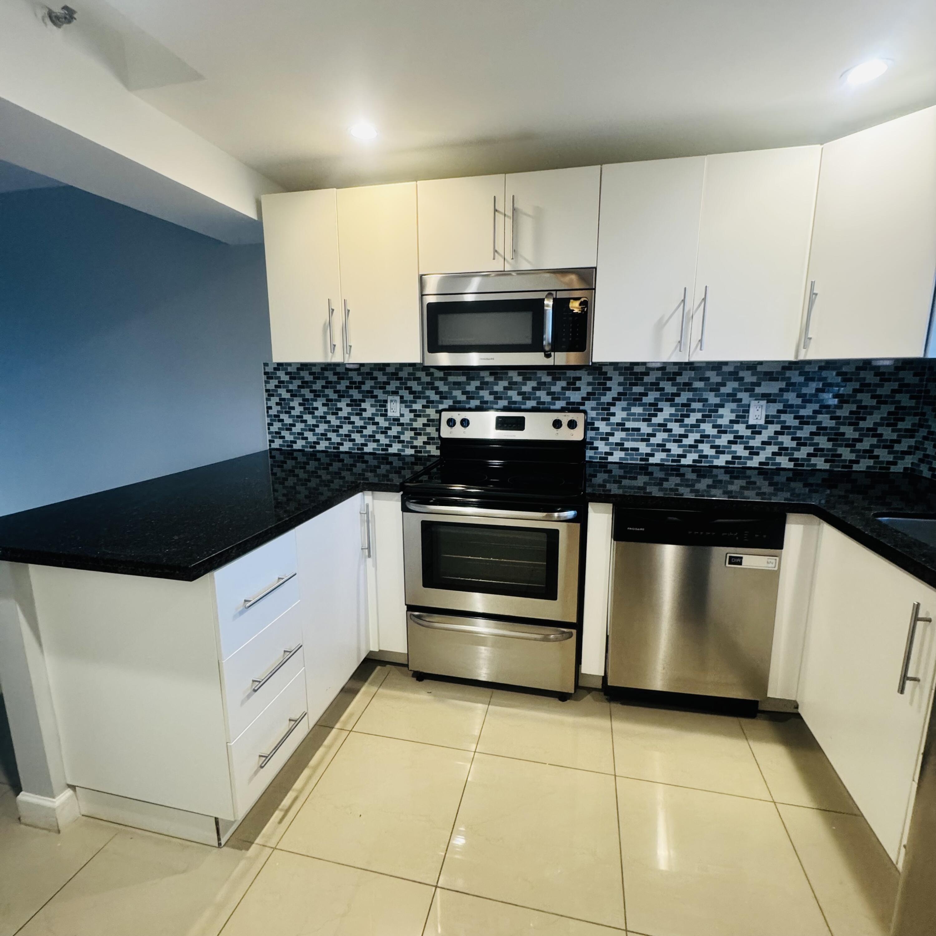 9235 Southwest 8th Street, Unit 503 Boca Raton, FL 33428 - Photo 1 of 17 a kitchen with white cabinets and stainless steel appliances