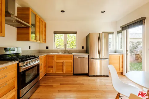 a kitchen with wooden floors and white stainless steel appliances