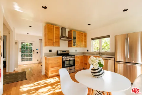 a kitchen with stainless steel appliances granite countertop a table chairs and a refrigerator