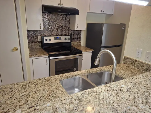 a view of a kitchen counter top space with stainless steel appliances wooden floor