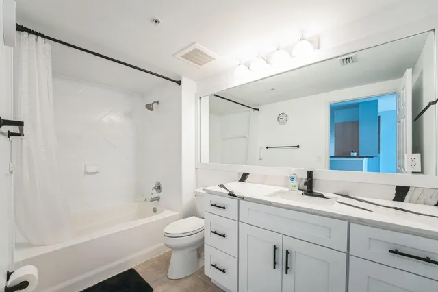 a bathroom with a double vanity sink toilet mirror and bathtub