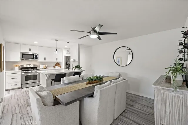 a kitchen with stainless steel appliances granite countertop a sink a stove top oven a chimney with wooden floor and cabinets