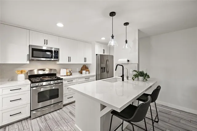 a kitchen with stainless steel appliances a stove a microwave a sink a stove a dining table and chairs