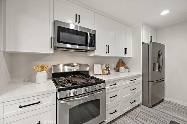 a kitchen with stainless steel appliances white cabinets white stove a microwave and a refrigerator