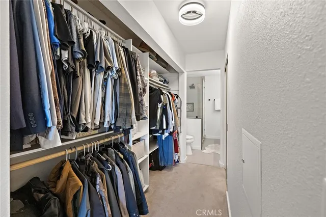 a view of walk in closet with clothes and shoes