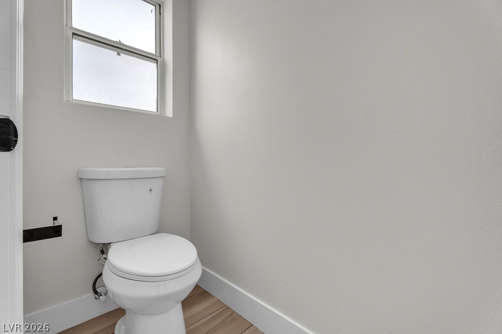 2139 Chapman Ranch Drive Henderson, NV 89012 - Photo 49 of 58 A well-lit, contemporary powder room featuring a toilet and a window for natural light.