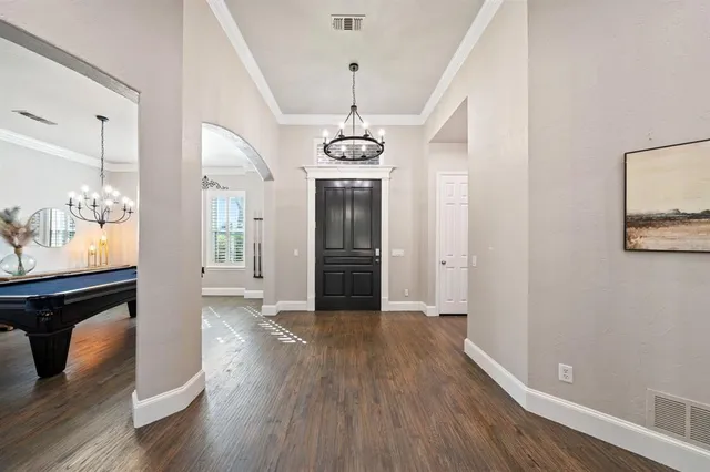 a view of a room with wooden floor chandelier and windows