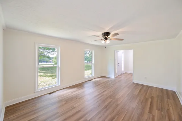 a view of an empty room with wooden floor and a window