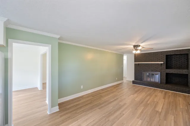 a view of a room with wooden floor fireplace and a window