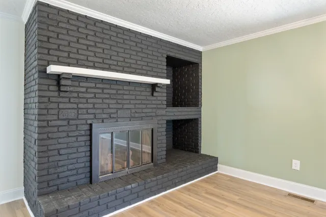 a view of an empty room with wooden floor and a fireplace