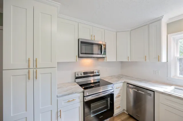 a kitchen with white cabinets and stainless steel appliances