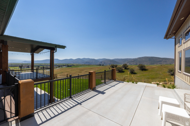 6117 North Rocky Ridge Road Peoa, UT 84061 - Photo 29 of 82 Spacious concrete patio with metal railing and stucco-clad posts, offering expansive landscape scenery