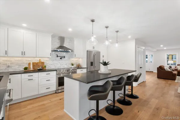a kitchen with kitchen island a dining table chairs stainless steel appliances and cabinets