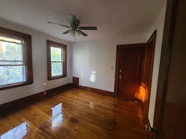 an empty room with wooden floor closet and windows