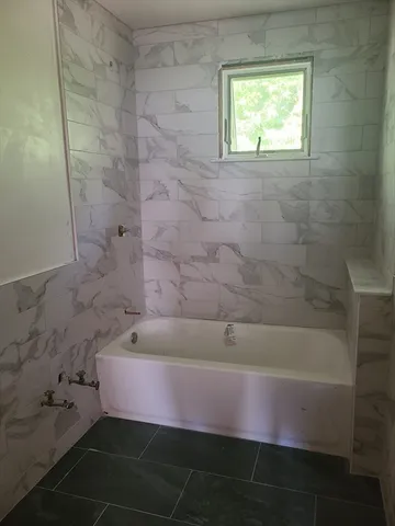 a bathroom with a granite countertop sink and a bathtub