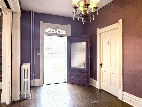a view of front door with hallway and wooden floor