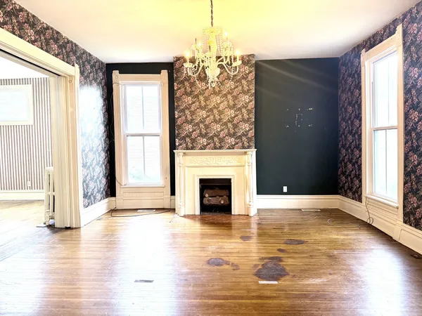 a view of a livingroom with wooden floor fireplace and windows