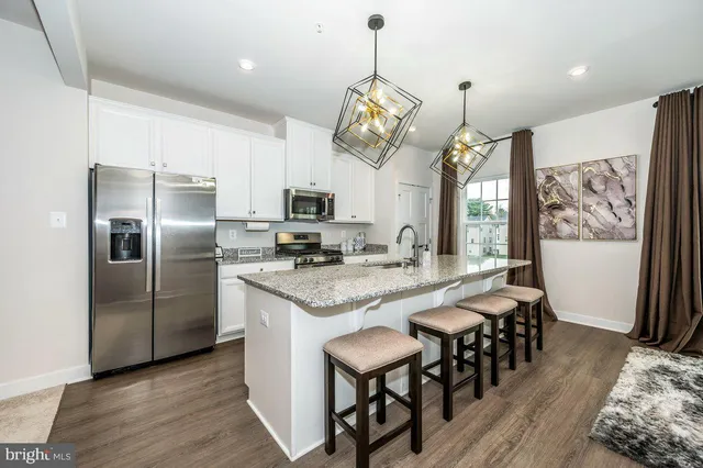 a kitchen with stainless steel appliances granite countertop a kitchen island hardwood floor and a sink