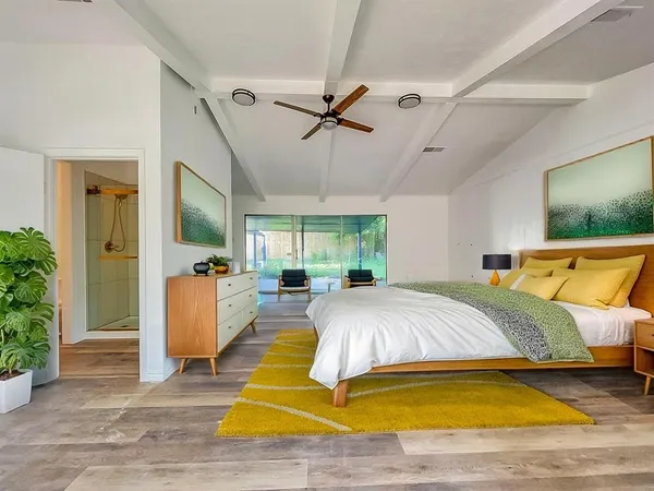 a spacious bedroom with a large bed a chandelier and windows