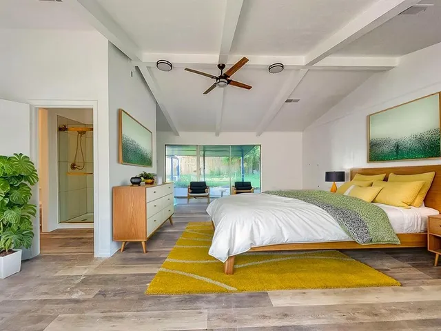 a spacious bedroom with a large bed a chandelier and windows