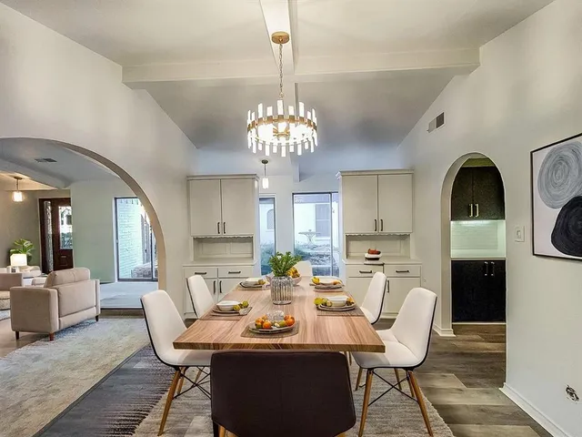 a dining room with wooden floor a chandelier a wooden table and chairs