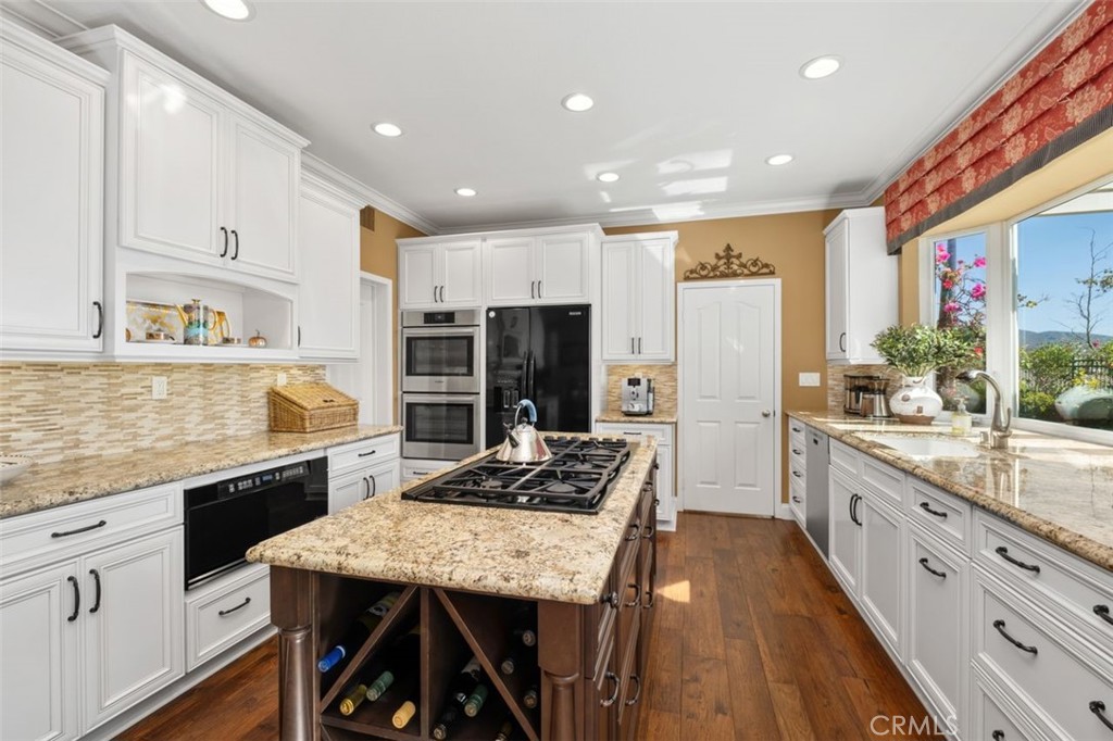 6 Muirfield Rancho Santa Margarita, CA 92679 - Photo 11 of 49 a kitchen with stainless steel appliances kitchen island granite countertop a table chairs in it and wooden floors
