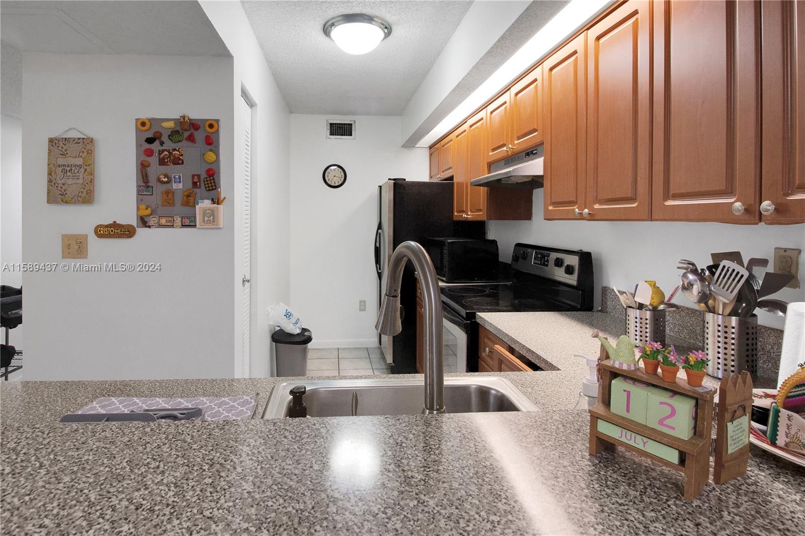 8650 Southwest 212th Street, Unit 101 Cutler Bay, FL 33189 - Photo 17 of 29 a kitchen with granite countertop a sink a stove and a microwave