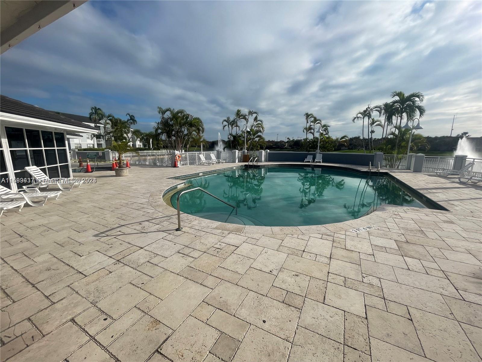 8650 Southwest 212th Street, Unit 101 Cutler Bay, FL 33189 - Photo 7 of 29 a view of a swimming pool with lawn chairs