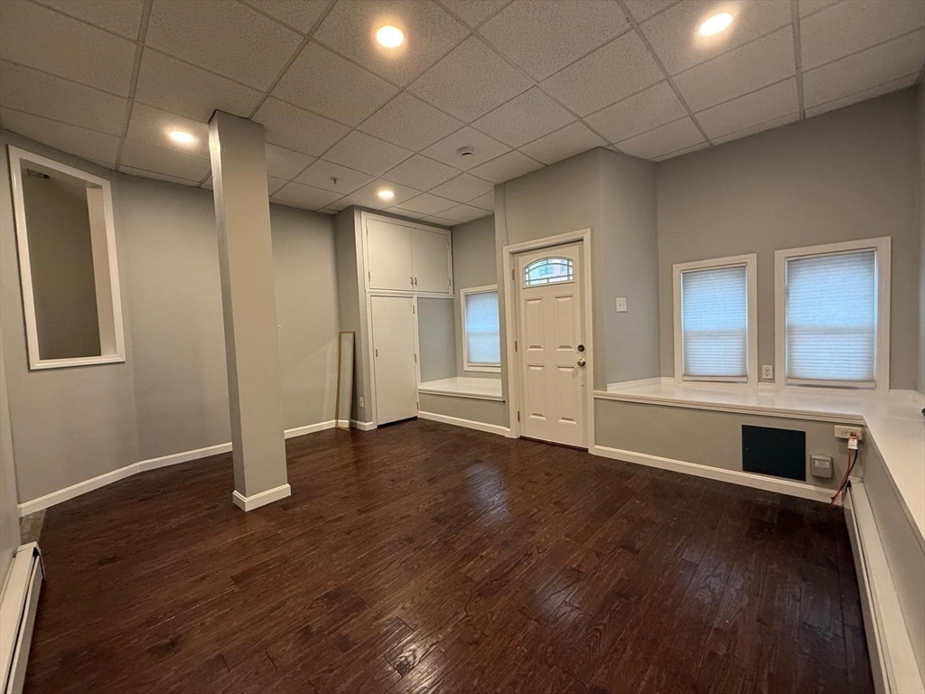 690 Lawrence Street, Unit 1 Lowell, MA 01852 - Photo 1 of 8 an empty room with wooden floor and windows