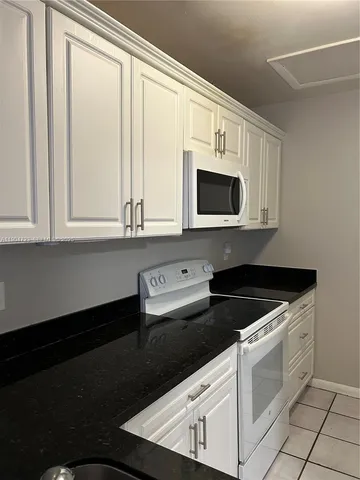 a kitchen with white cabinets and black appliances