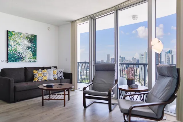 a living room with furniture kitchen view and a large window