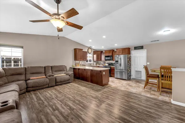 a kitchen with stainless steel appliances kitchen island granite countertop a refrigerator and a dining table