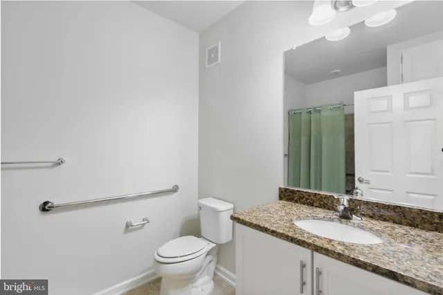 a bathroom with a granite countertop sink a toilet and a mirror