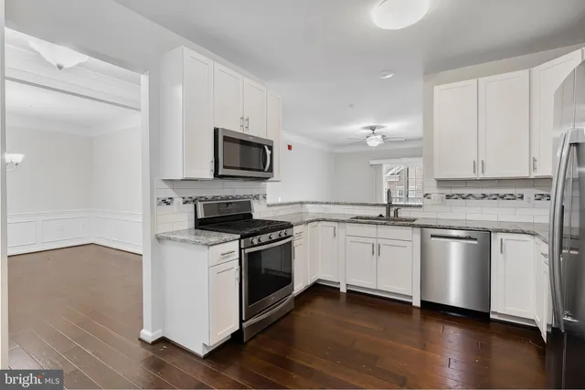 a kitchen with granite countertop a sink cabinets and stainless steel appliances