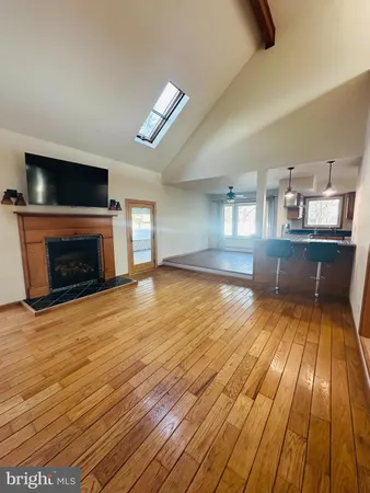 an empty room with wooden floor fireplace and windows
