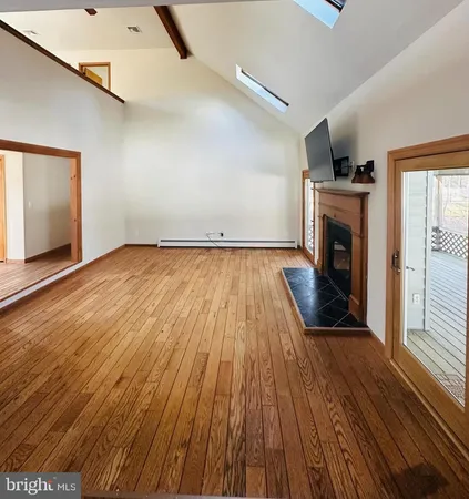 an empty room with wooden floor fireplace and windows