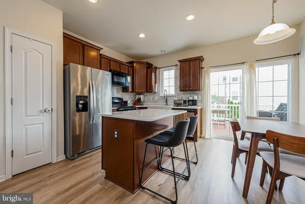 a kitchen with stainless steel appliances granite countertop a refrigerator a stove a sink a dining table and chairs with wooden floor