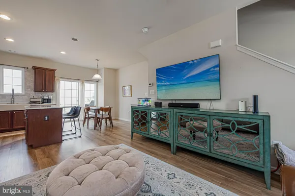 a living room with furniture a flat screen tv and kitchen view